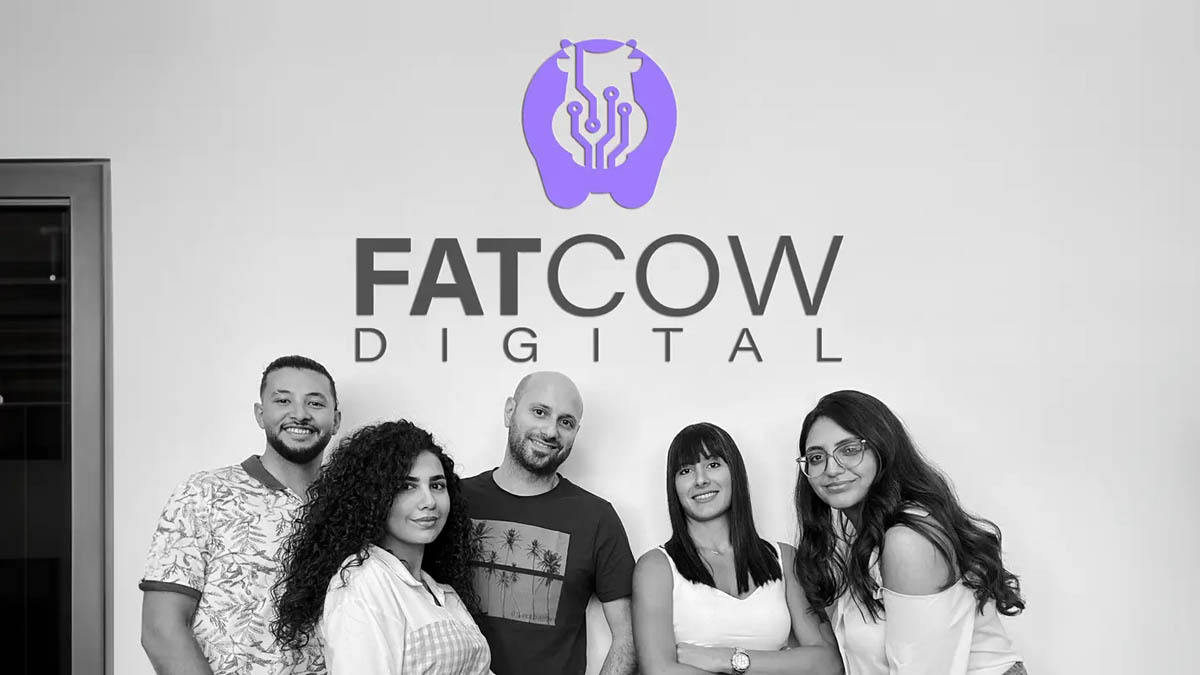 Original Team of Fatcow Digital with company logo on wall behind them - close up