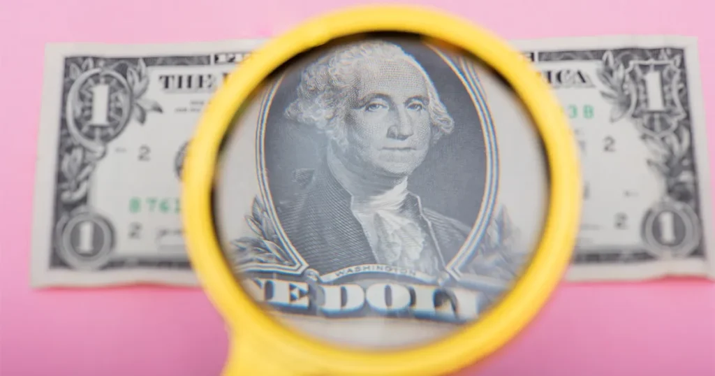 an image of a one dollar bill with a magnifier glass on the washington section being magnified